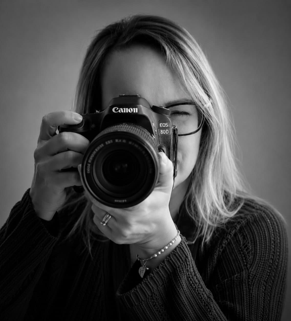 Mélanie, photographe, portrait en noir et blanc derrière son appareil photo